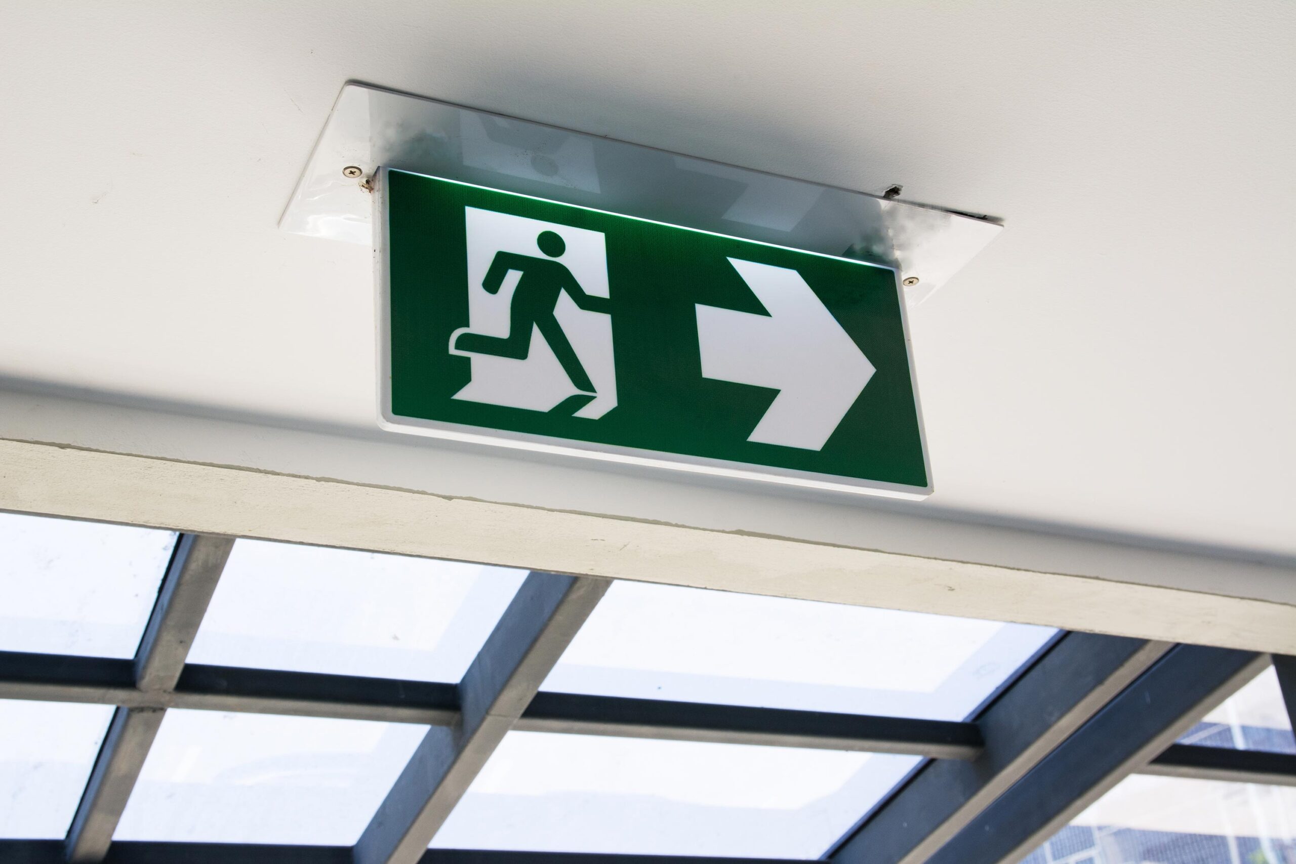 .Green fire escape sign hang on the white ceiling