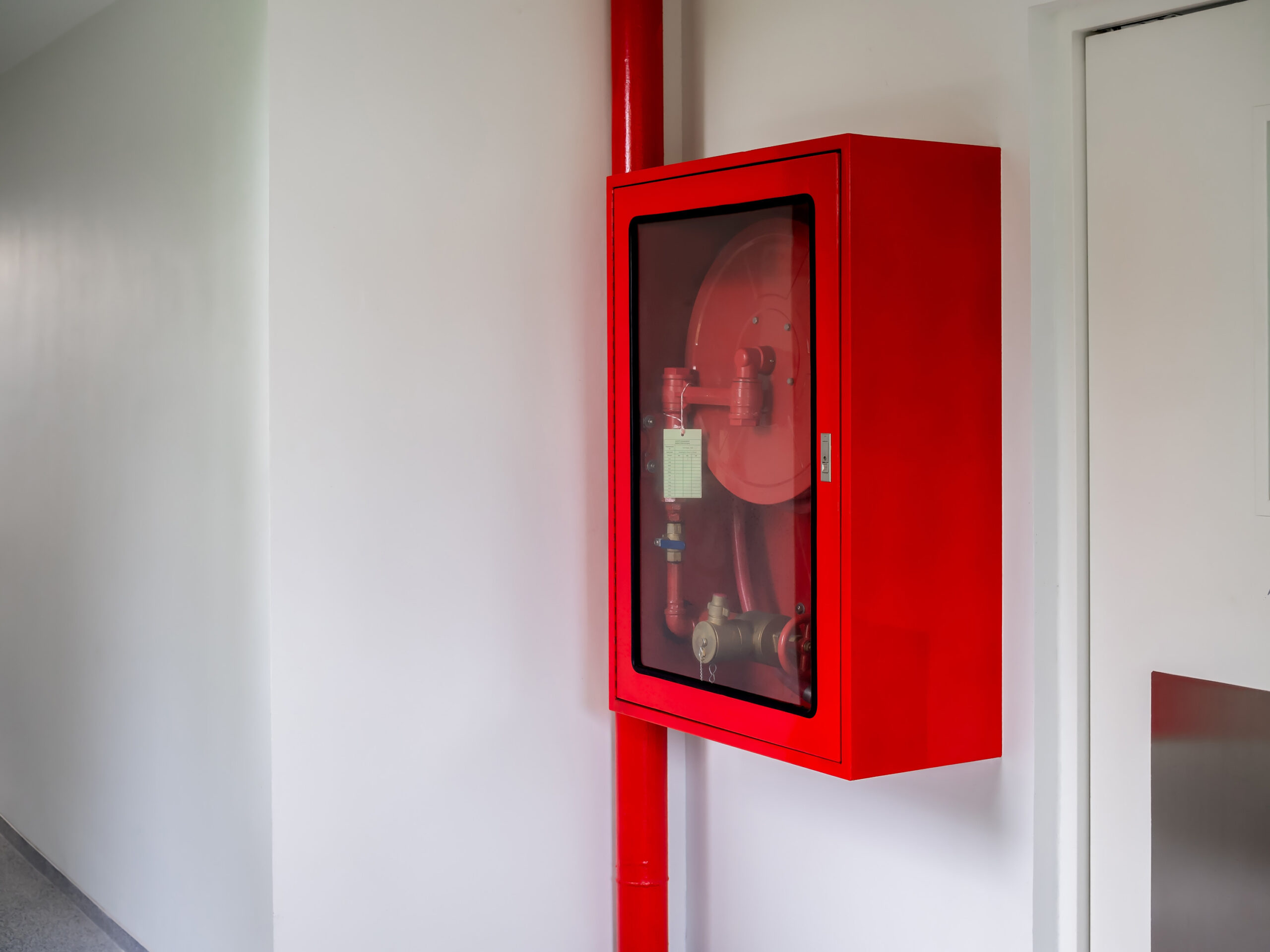 Fire extinguisher cabinet mounted on the wall in the corner of the white wall